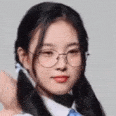 a close up of a girl wearing glasses and two pigtails .