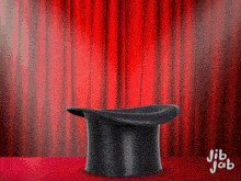 a top hat sits on a table in front of a red curtain with jib jab written on the bottom