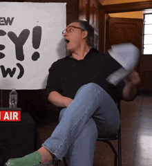 a man sitting in front of a sign that says " ew "