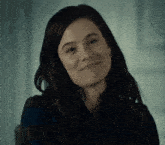 a woman with long dark hair is smiling and wearing earrings