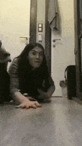 a woman is crawling on a wooden floor in a hallway