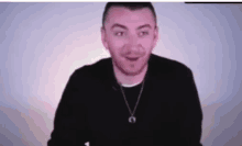 a man wearing a necklace is making a funny face while looking at the camera .