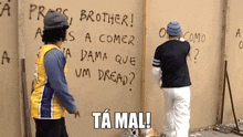 two men are standing in front of a wall that has graffiti on it including the word brother