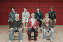a group of young men are sitting in chairs with one wearing a red jacket that says ' i love you '
