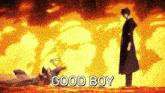 a man in a black coat is standing in front of a fire with the words good boy written below him