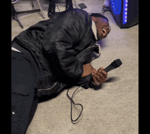 a man is laying on the floor with a microphone in his hand