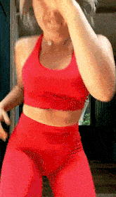 a woman in a red sports bra and red pants is dancing .