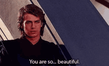 a man is standing in front of a blue wall and saying `` you are so ... beautiful . ''