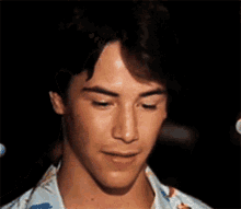 a close up of a man 's face with a floral shirt on