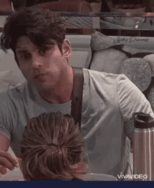 a man and a woman are sitting at a table . the man is looking at the woman 's hair .