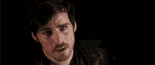 a close up of a man 's face with a beard and a black jacket .