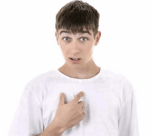 a young man in a white shirt is pointing at his chest with his finger .