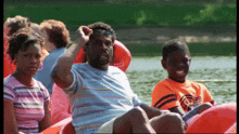 a man wearing sunglasses sits next to a boy wearing an orange shirt that says basketball