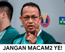 a man wearing glasses and a green shirt says jangan macam2 ye!
