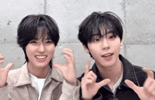 two young men are making a heart shape with their hands and one of them is wearing a white shirt that says knit out