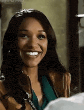a woman is smiling and looking at the camera while wearing a brown jacket .