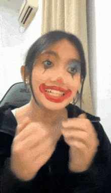 a woman is wearing a clown costume and making a funny face .