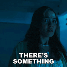 a woman in a dark room with the words " there 's something " above her
