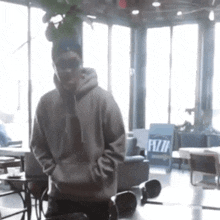 a man in a hoodie is kneeling down in a room with a sign that says pizza on it .