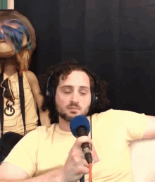 a man wearing headphones holds a microphone in front of a stuffed animal with a g on it