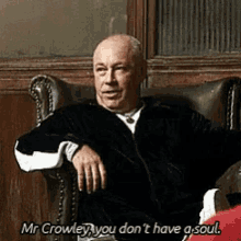 a man is sitting in a chair saying mr crowley you don t have a soul