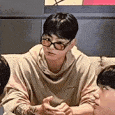 a man wearing glasses is sitting at a table with other people .