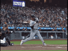a baseball player swings at a pitch in front of a cutwater banner