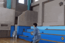 a man in a blue jacket is walking down a set of stairs in a building .