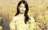 a woman in a yellow off the shoulder top is standing in front of a yellow background .