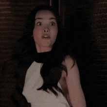 a woman in a white top and black top is making a surprised face