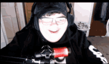 a man wearing headphones and glasses is smiling in front of a microphone
