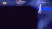 a man in a bun is waving his hand in the air while standing on a stage .