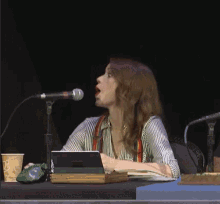 a woman sitting at a table with a microphone and a tablet that says ' microsoft ' on it