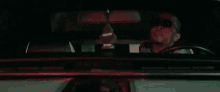 a man is sitting in the driver 's seat of a car talking on a cell phone .