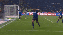 a soccer player is running on a field with a sky sport ad behind him