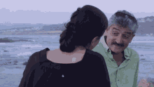 a man in a green shirt is talking to a woman in a black shirt with the letter a above them