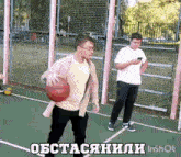 a man is holding a basketball on a basketball court while another man looks on .