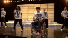 a man in a wheelchair is wearing a white shirt that says four eyes