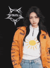 a woman wearing an orange jacket and a white shirt with a sun on it stands in front of a black background that says unaya