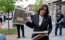 a woman in a suit is holding a picture of a park bench in the woods