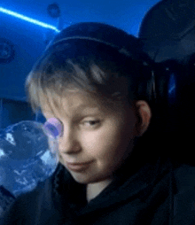 a young boy wearing headphones and glasses is sitting in a chair in a dark room .