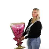 a woman wearing a sash that says happy birthday is holding a large balloon