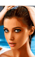a close up of a woman 's face with blue eyes holding her hair