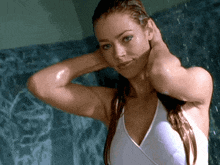 a woman in a white bathing suit is standing in a shower