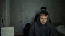 two men are fighting in a room with a laptop in the foreground .