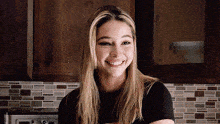 a woman with blonde hair is smiling in a kitchen .