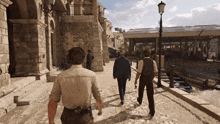three men are walking down a cobblestone street in a city