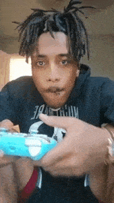 a man with dreadlocks is playing a video game with a controller