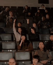 a group of people sitting in a theater with the letter h on the bottom left