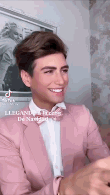 a man in a pink suit and bow tie is smiling in front of a picture of marilyn monroe